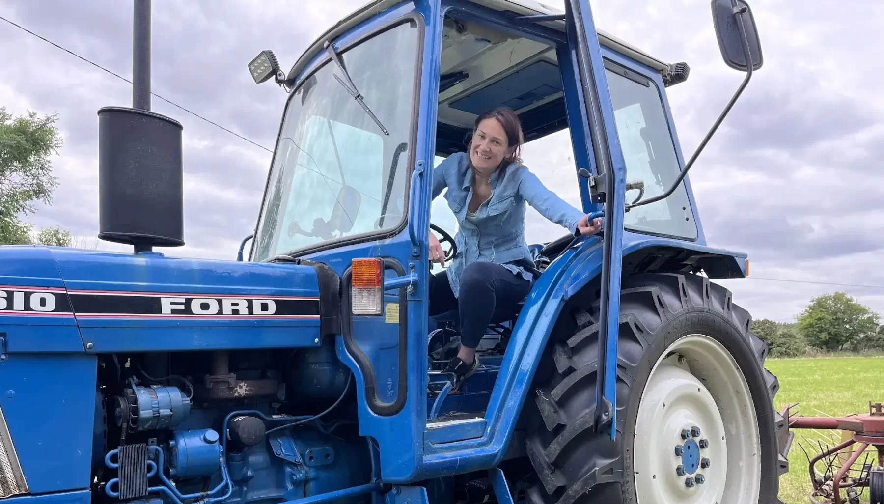 Senator Erin McGreehan sitting in in a blue ford tractor.looking out the opened door.