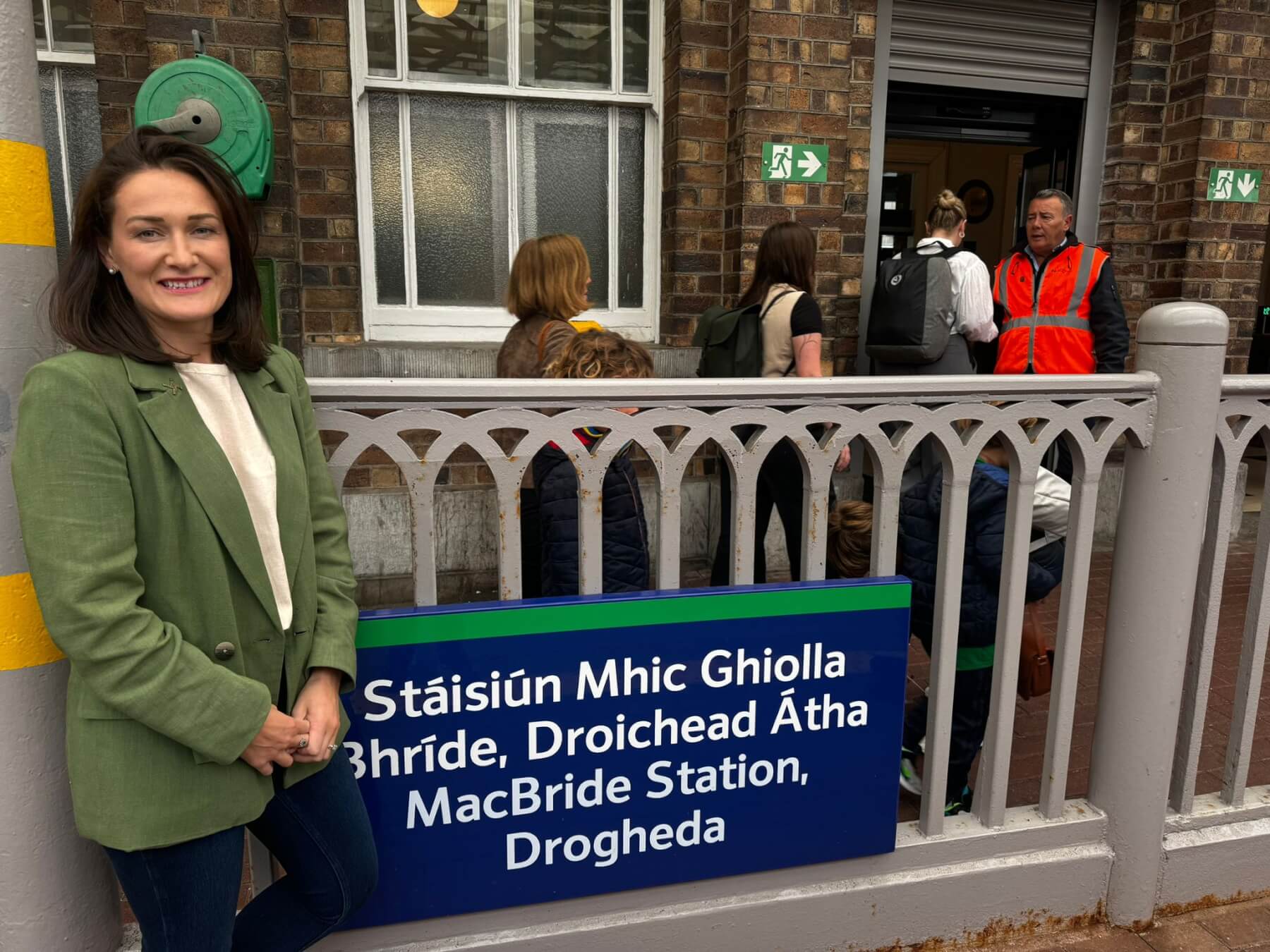 Senator Erin McGreehan standing with a green blazer next to a sign saying MacBride Train Station Drogheda